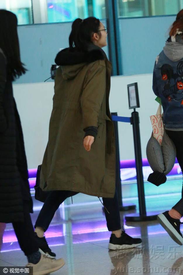 刘雯素颜戴框镜现身机场 军绿色大衣走帅气风