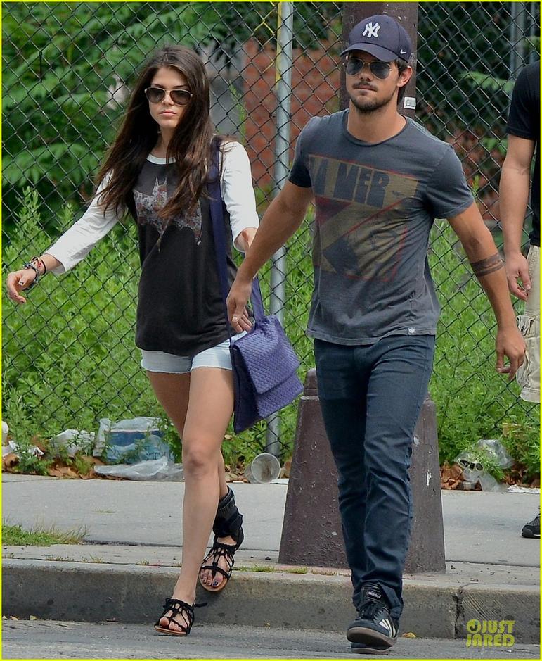 2013年7月30日讯,纽约,当地时间7月29日,21岁的狼人泰勒-洛特纳(Taylor Lautner)携27岁的女星玛丽-艾格洛浦路斯( Marie Avgeropoulos)亮相街头。一身休闲装难掩好身材的特洛纳与女友十指紧扣现身,更不时握着手机在街头自拍,大秀恩爱。
